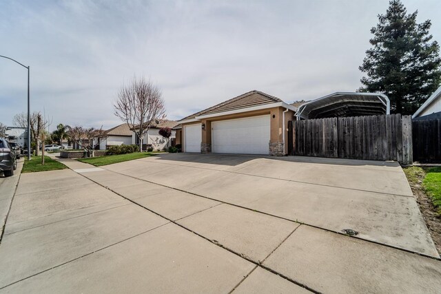 view of front facade featuring an attached garage, fence, stucco siding, a carport, and driveway