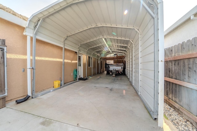 view of parking / parking lot with a carport and fence