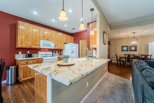 kitchen featuring white appliances, light stone countertops, visible vents, a peninsula, and a sink