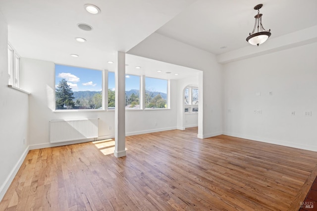 empty room with recessed lighting, baseboards, light wood-style floors, and radiator heating unit