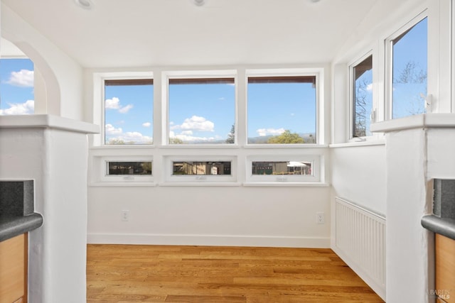 unfurnished sunroom featuring a healthy amount of sunlight and radiator heating unit