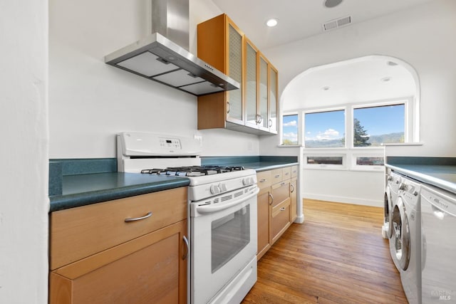 kitchen with visible vents, white gas stove, dishwasher, wall chimney range hood, and washer and clothes dryer