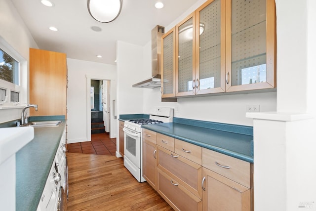 kitchen featuring light wood-type flooring, a sink, gas range gas stove, recessed lighting, and wall chimney range hood