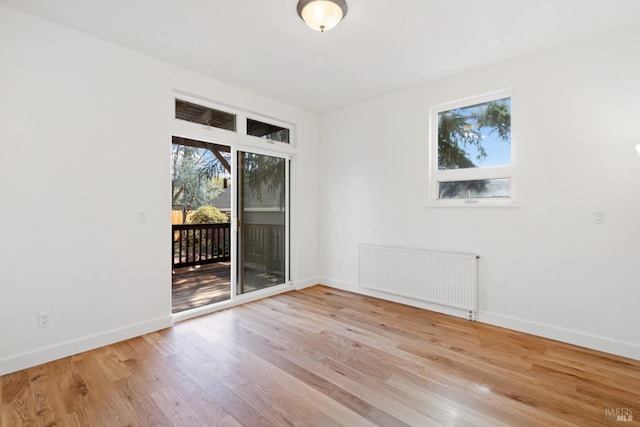 spare room featuring baseboards, radiator, and wood finished floors