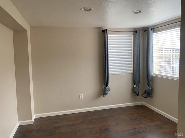 empty room with recessed lighting, baseboards, a textured ceiling, and wood finished floors