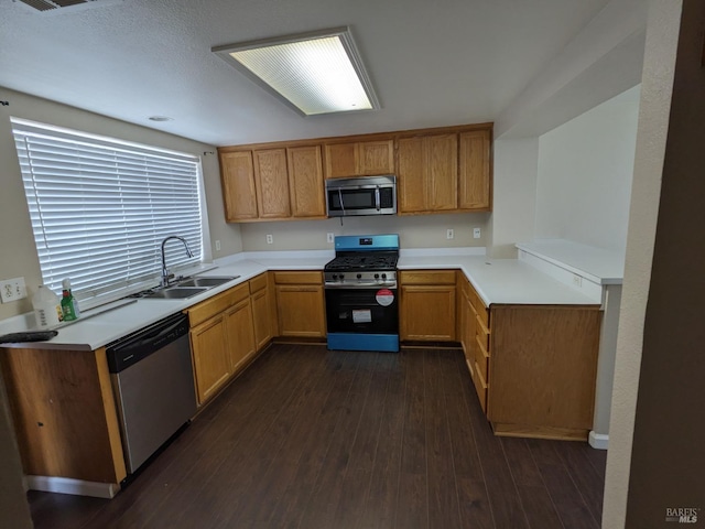 kitchen featuring dark wood finished floors, light countertops, appliances with stainless steel finishes, and a sink