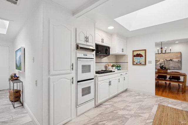 kitchen with backsplash, white cabinetry, black appliances, and a skylight