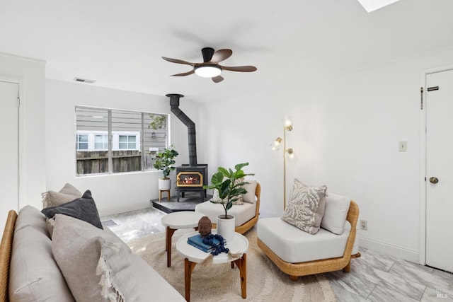 living area with visible vents, marble finish floor, a wood stove, and ceiling fan