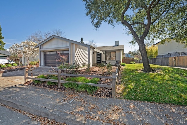 view of front of property with a front lawn, an attached garage, driveway, and fence