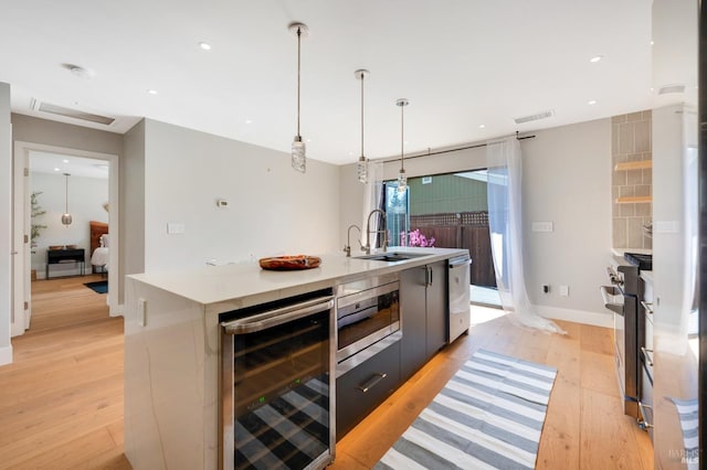 kitchen with visible vents, beverage cooler, a sink, light wood-style floors, and appliances with stainless steel finishes