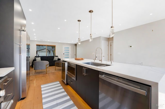 kitchen with appliances with stainless steel finishes, modern cabinets, light countertops, and a sink