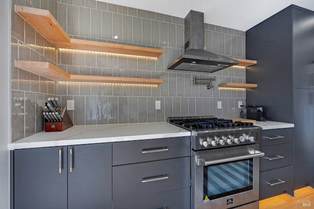 kitchen featuring open shelves, wall chimney range hood, stainless steel stove, and tasteful backsplash