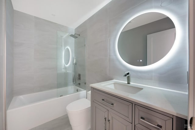 bathroom with vanity, tile walls,  shower combination, and toilet