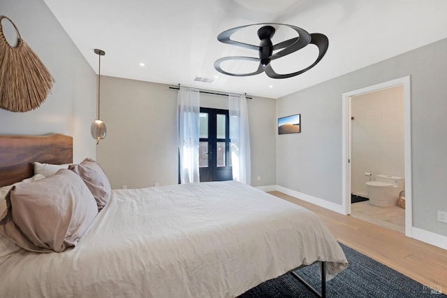 bedroom featuring wood finished floors, visible vents, baseboards, french doors, and ensuite bathroom