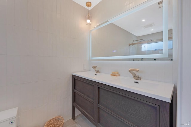 bathroom featuring tile patterned flooring, visible vents, vanity, tiled shower, and tile walls