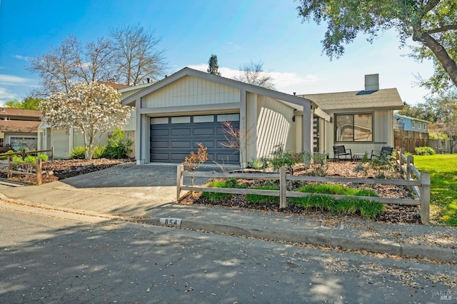 view of front facade with a chimney, concrete driveway, a garage, and fence