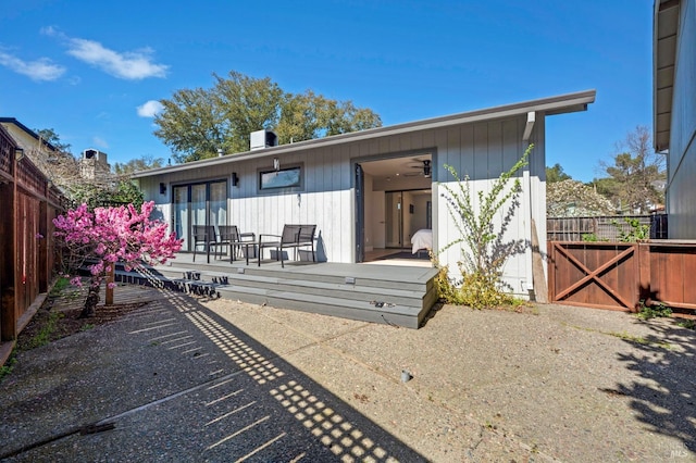 rear view of property with a gate, a patio area, a wooden deck, and fence