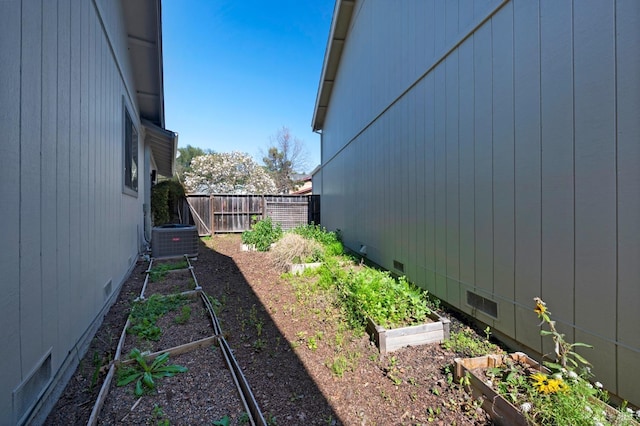 view of yard featuring a garden, cooling unit, and fence