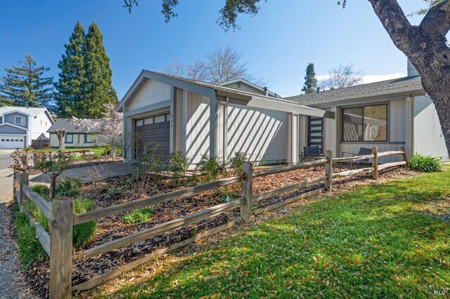 view of front of house featuring a front yard, an attached garage, and fence