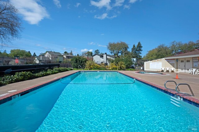 pool featuring a community hot tub, a patio, and fence