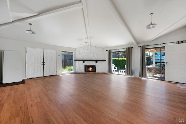 unfurnished living room with beam ceiling, high vaulted ceiling, wood finished floors, and a fireplace