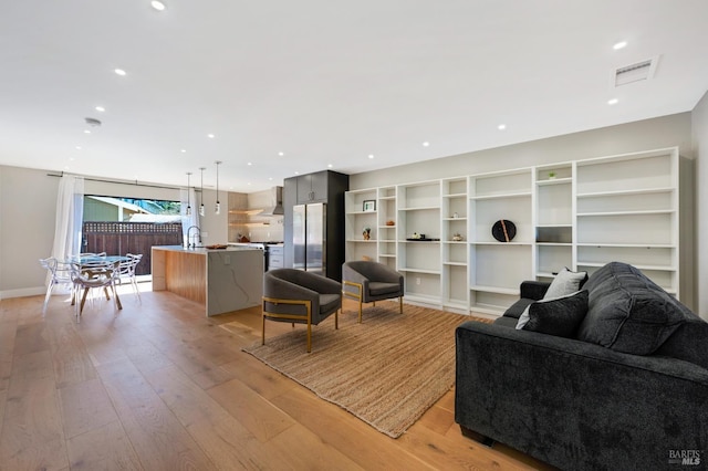 living room with recessed lighting, visible vents, light wood finished floors, and baseboards