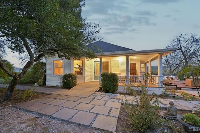 back of property featuring a shingled roof and covered porch