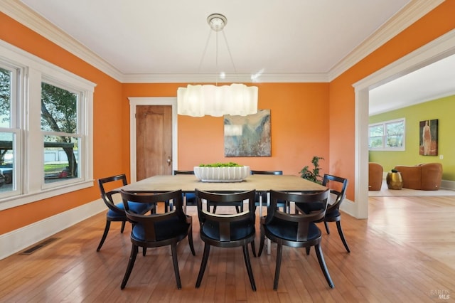 dining room featuring ornamental molding, light wood-style flooring, baseboards, and visible vents