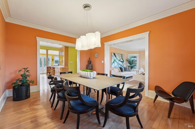 dining room featuring baseboards, light wood finished floors, ornamental molding, and a healthy amount of sunlight