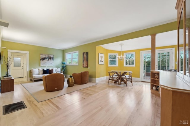living room featuring baseboards, an inviting chandelier, visible vents, crown molding, and wood finished floors