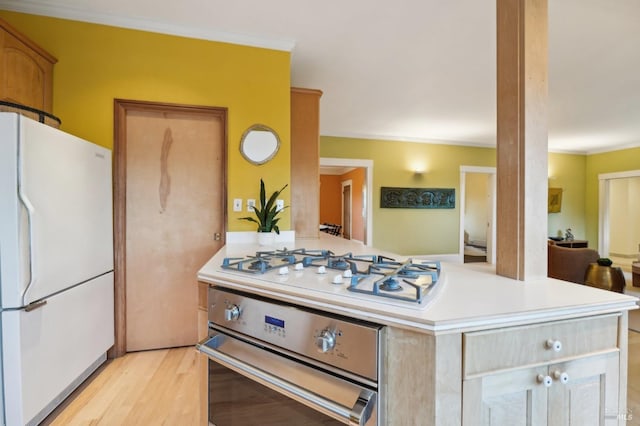 kitchen featuring light countertops, light wood-style flooring, ornamental molding, and white appliances