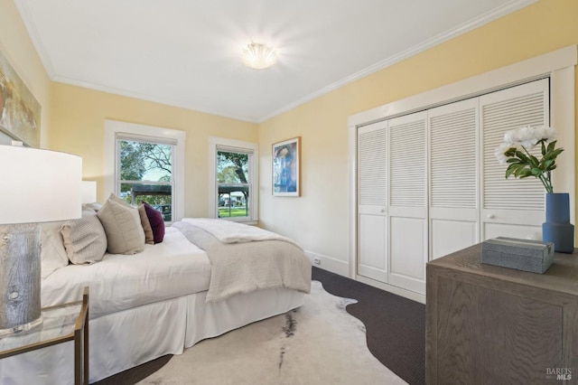 carpeted bedroom with baseboards, ornamental molding, and a closet