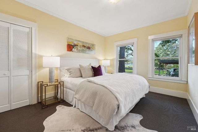 bedroom with baseboards, dark carpet, a closet, and crown molding