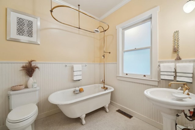 bathroom with toilet, wainscoting, visible vents, a freestanding bath, and crown molding