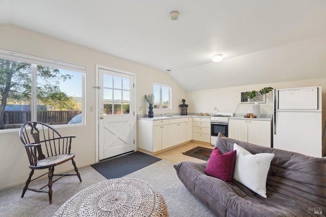 living room with light colored carpet, vaulted ceiling, and baseboards