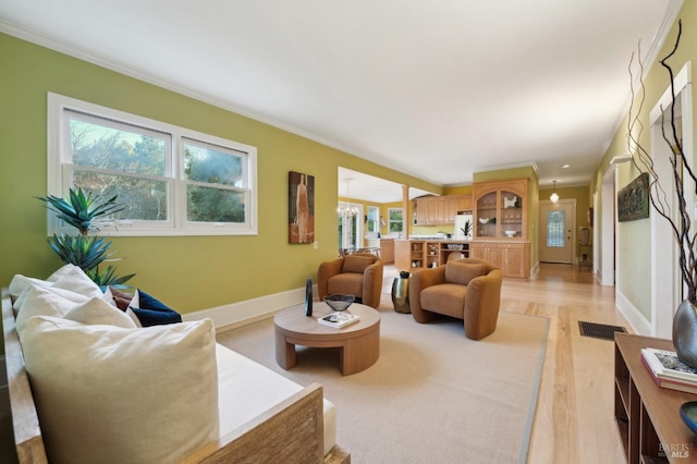 living area with baseboards, crown molding, and plenty of natural light
