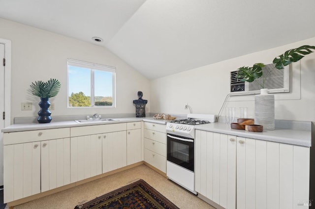 kitchen featuring white gas range oven, lofted ceiling, a sink, and light countertops