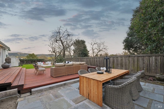 view of patio / terrace with a storage shed, outdoor dining space, a fenced backyard, a wooden deck, and an outdoor hangout area