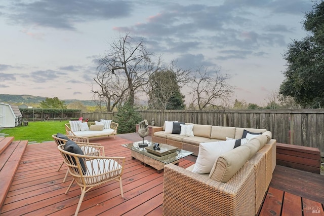 deck featuring outdoor lounge area, an outdoor structure, a fenced backyard, a shed, and a yard