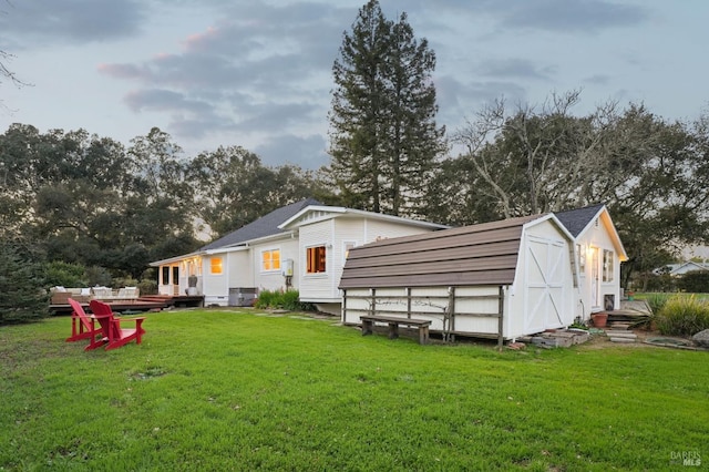 back of property featuring an outdoor structure, a lawn, and a shed
