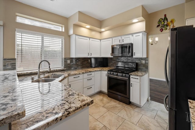 kitchen with backsplash, light stone counters, appliances with stainless steel finishes, and a sink