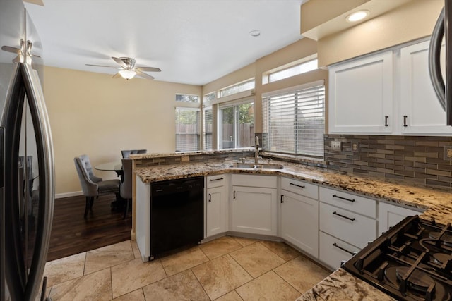 kitchen featuring backsplash, a peninsula, white cabinets, black appliances, and a sink