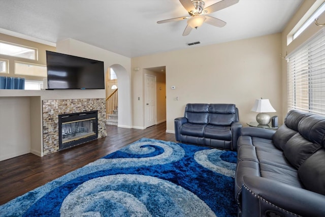 living room with wood finished floors, a fireplace, visible vents, and ceiling fan