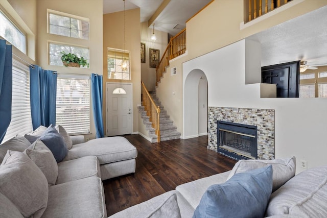 living room with visible vents, baseboards, stairway, a fireplace, and wood finished floors