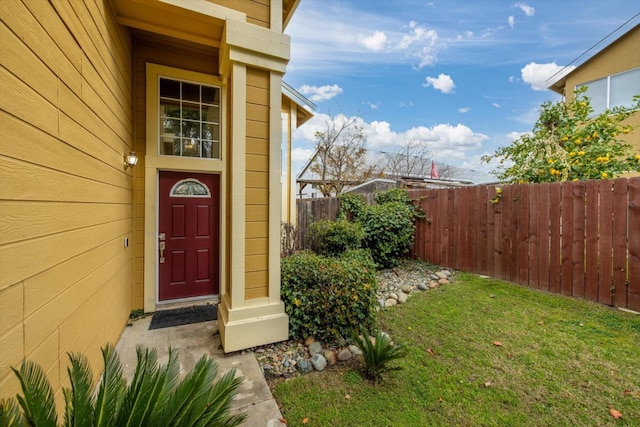 doorway to property with a yard and fence