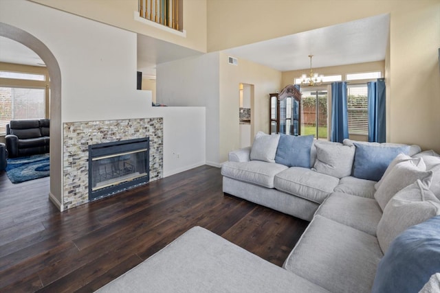 living area with visible vents, wood finished floors, a fireplace, baseboards, and a chandelier