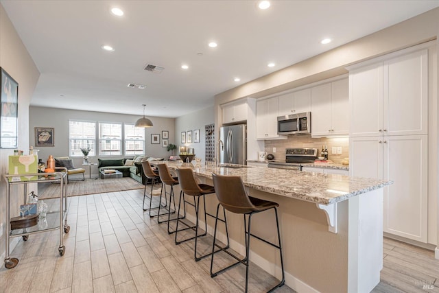 kitchen with white cabinetry, visible vents, a kitchen breakfast bar, and appliances with stainless steel finishes