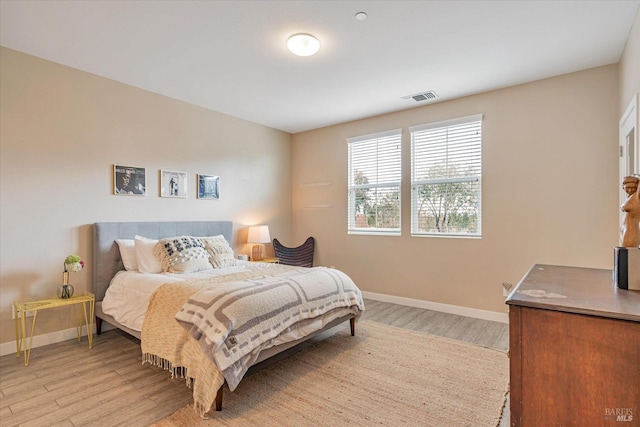 bedroom featuring baseboards, visible vents, and light wood finished floors