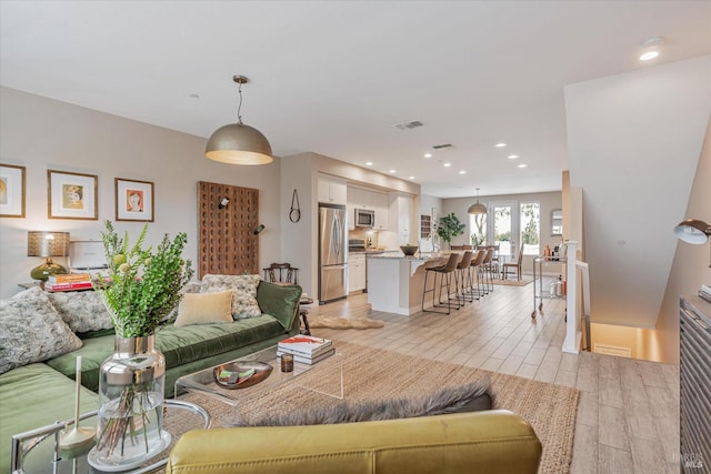 living area with visible vents, light wood-style floors, and recessed lighting
