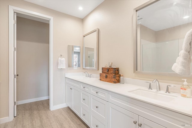 bathroom with baseboards, double vanity, a sink, and wood finished floors